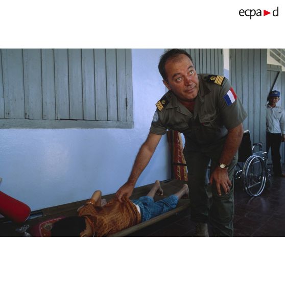 Un médecin-chef militaire de l'APRONUC ausculte un enfant à l'hôpital de Sihanoukville.