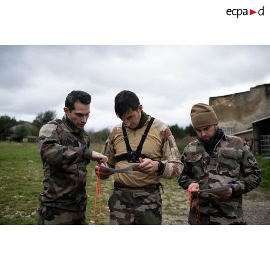 L'officier image Maxime s'oriente sur une carte aux côtés de l'opérateur vidéo Julien et du photographe Simon pour une course d'orientation sur le camp de Causse.