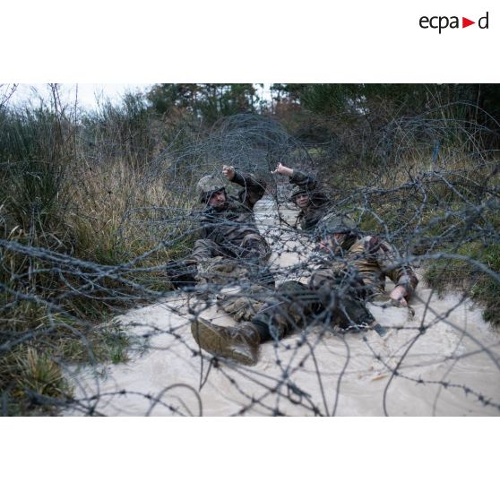 L'opérateur vidéo Julien et le photographe Simon aident l'officier image Maxime à passer un réseau de barbelés sur la piste commando du camp de Causse.