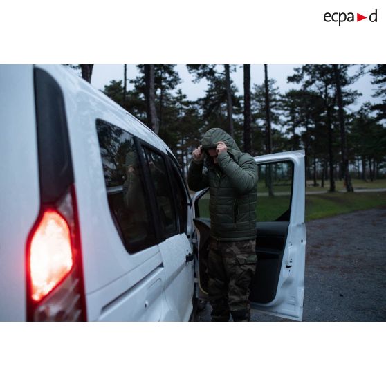 Le photographe Simon ajuste sa capuche avant d'embarquer à bord d'une voiture sur le camp de Causse.