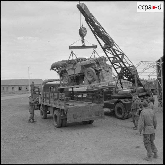 Parachutistes du centre de Blida. Chargement d'une jeep dans un camion.