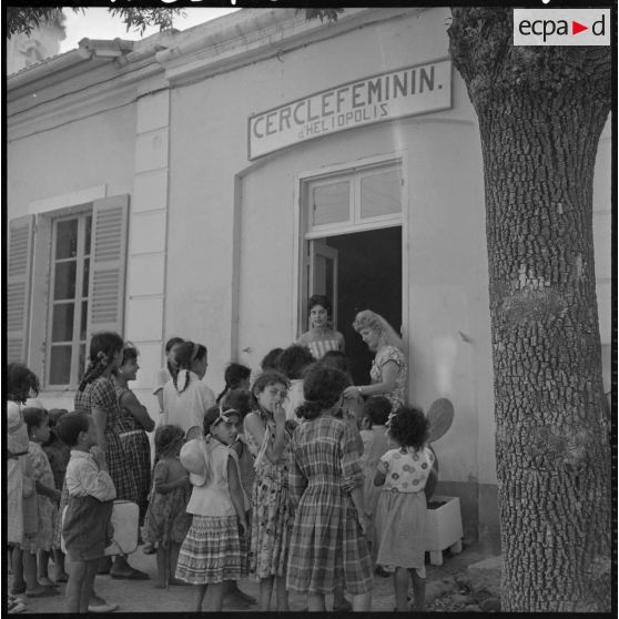 Des enfants et des jeunes filles sont rassemblés devant l'entrée du Cercle féminin d'Héliopolis.