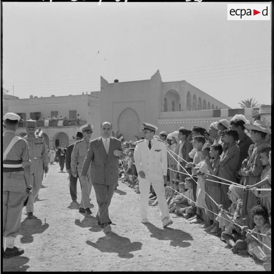 André Jacomet défile devant la foule rassemblée à Bou Saâda à l'occasion de son discours, accompagné par des autorités militaires.