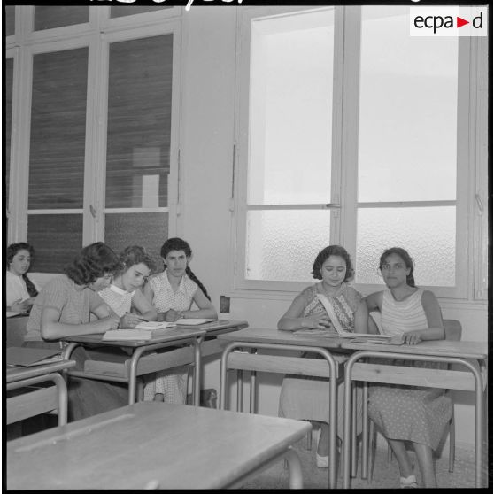 Jeunes femmes destinées à devenir monitrices assises à des bureaux dans une salle de classe.