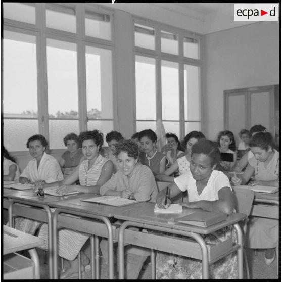 Jeunes femmes destinées à devenir monitrices assises à des bureaux dans une salle de classe.