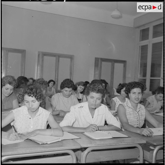 Jeunes femmes destinées à devenir monitrices assises à des bureaux dans une salle de classe.