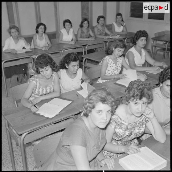 Jeunes femmes destinées à devenir monitrices assises à des bureaux dans une salle de classe.