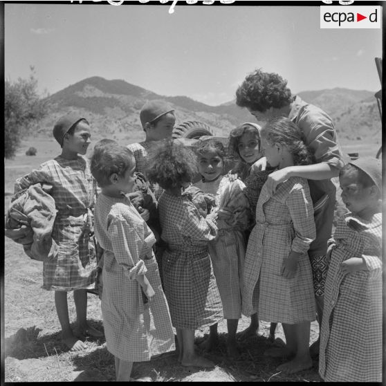 Après la séance du bain dans l'oued et la distribution de tabliers, les jeunes enfants entourent une éducatrice des équipes médico-sociales itinérantes (EMSI) d'Affreville.