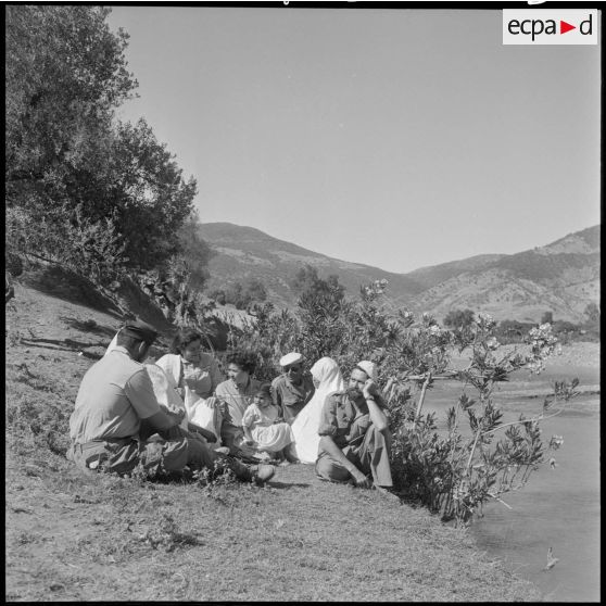 Des hommes du poste de Bou Maad en conversation avec des femmes et des éducatrices des équipes médico-sociales itinérantes (EMSI) au bord de l'oued.