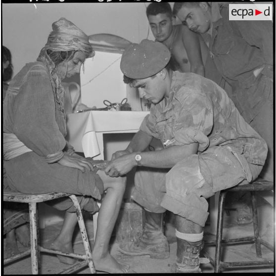 A l'intérieur de l'infirmerie, un légionnaire du 1er régiment étranger parachutiste (1er REP) fait un pansement à une femme du village.