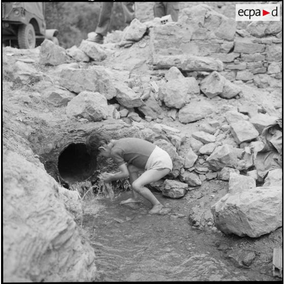 Un jeune garçon fait sa toilette dans une source de montagne, à l'intérieur des roches.