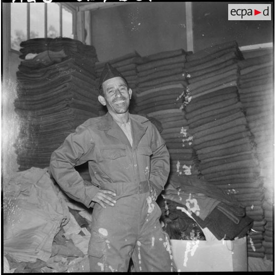 Portrait d'un harki qui pose dans sa nouvelle tenue à l'intérieur du magasin d'habillement de Palestro.