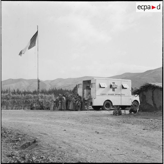 Rassemblement de la population du centre de regroupement de Talouine, situé dans la vallée de l'Oued Isser, devant le camion de la Croix-Rouge française.