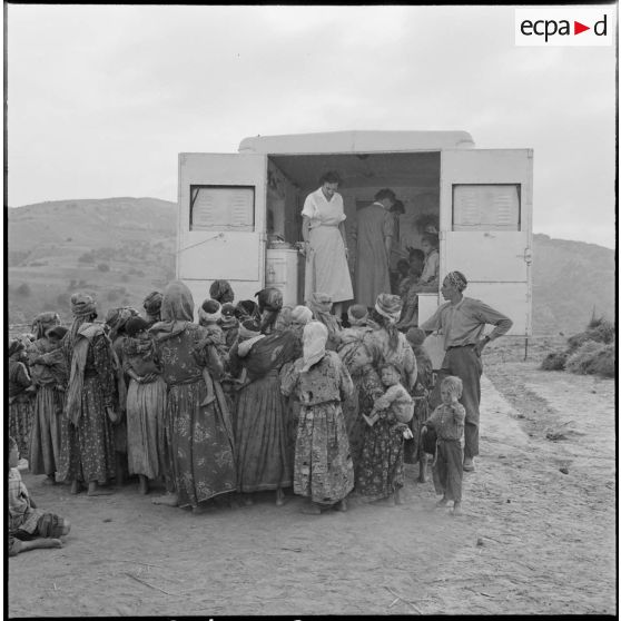 Rassemblement de la population du centre de regroupement de Talouine, situé dans la vallée de l'Oued Isser, devant le camion de la Croix-Rouge française.