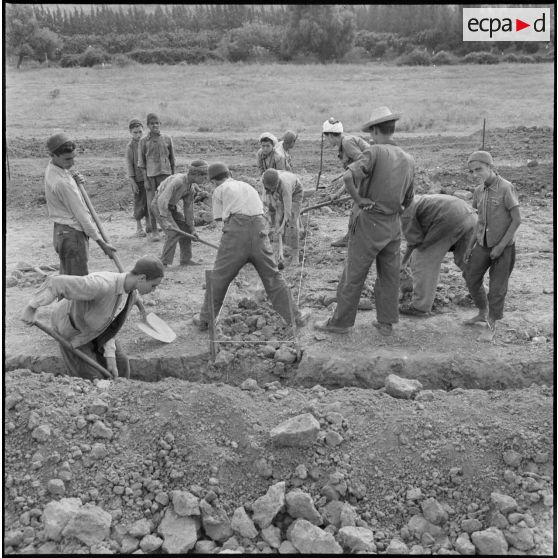 Les enfants du centre de regroupement de Taliouine, situé dans dans la vallée de l'Oued Isser, participent à l'édification de leur école.