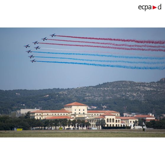 Les avions Alphajet de la Patrouille de France volent en formation Grande flèche au-dessus du bâtiment de la direction et l'enseignement (BDE) de la base aérienne (BA) 701 de Salon-de-Provence.