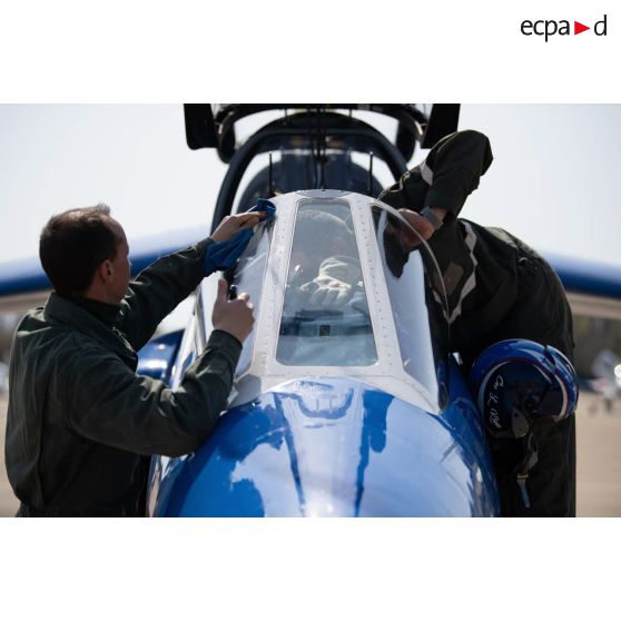 Des mécaniciens nettoient la verrière du cockpit d'un avion Alphajet de la Patrouille de France pour le premier vol de la journée sur la base aérienne (BA) 701 de Salon-de-Provence.