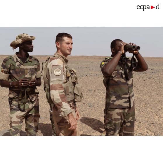 Un soldat malien observe une zone de tir au moyen de jumelles Vector 21 sous la supervision d'un artilleur du 93e régiment d'artillerie de montagne (RAM) à Tessalit, au Mali.