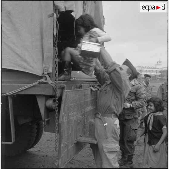 Enfant de harki partant pour la France aidé par les soldats du 26e régiment d'infanterie motorisé (RIM).