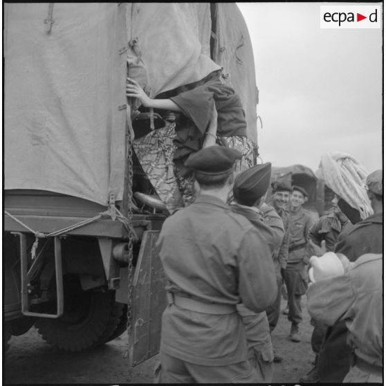 Femme de harki partant pour la France aidée par les soldats du 26e régiment d'infanterie motorisé (RIM).