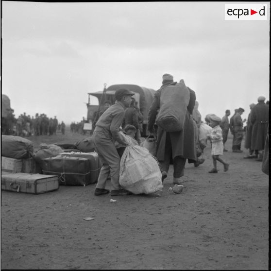 Familles de harkis partant pour la France aidées par les soldats du 26e régiment d'infanterie motorisé (RIM).