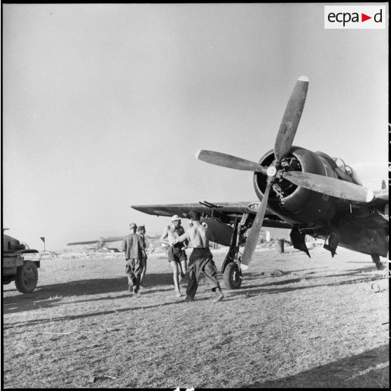 Fixation d'une roquette sous les plans d'un avion de chasse Bearcat sur le terrain d'aviation de Diên Biên Phu.