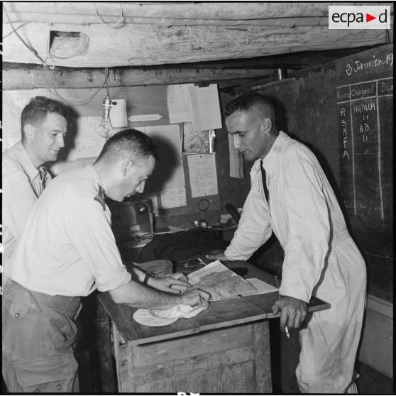 Briefing entre un pilote et un lieutenant dans un bureau souterrain du camp de Diên Biên Phu.