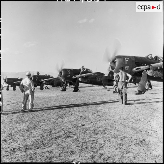 Sous l'oeil des mécaniciens, des avions de chasse Bearcat font le point fixe avant de décoller.