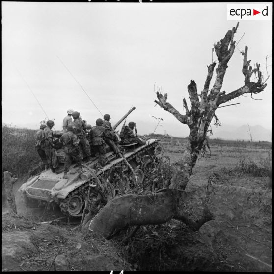 Progression d'un char M24 Chaffee de l'escadron de marche du 1er régiment de chasseurs à cheval (RCC) transportant des fantassins au cours d'une offensive contre des positions de l'Armée populaire vietnamienne à Diên Biên Phu.