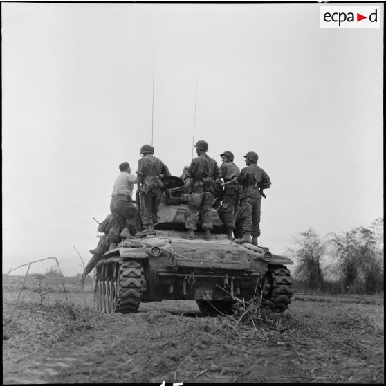 Progression d'un char M24 Chaffee de l'escadron de marche du 1er régiment de chasseurs à cheval (RCC) transportant des fantassins au cours d'une offensive contre des positions de l'Armée populaire vietnamienne à Diên Biên Phu.