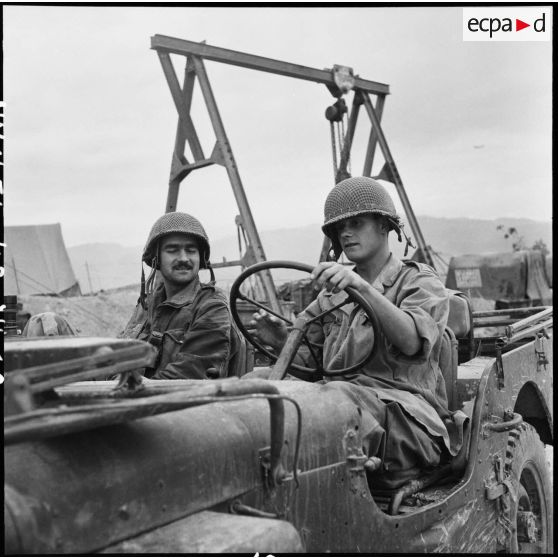 Le cameraman Pierre Schoendoerffer et le photographe Daniel Camus du Service presse information (SPI) assis dans une jeep à Diên Biên Phu.