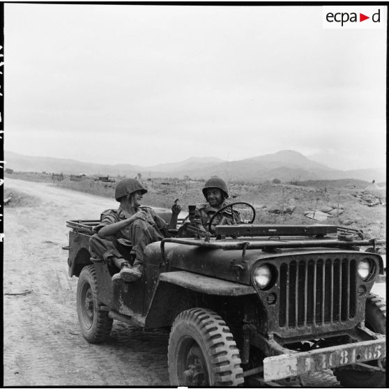 Le cameraman Pierre Schoendoerffer et le photographe Jean Peraud du Service presse information (SPI) plaisantant dans une jeep à Diên Biên Phu.