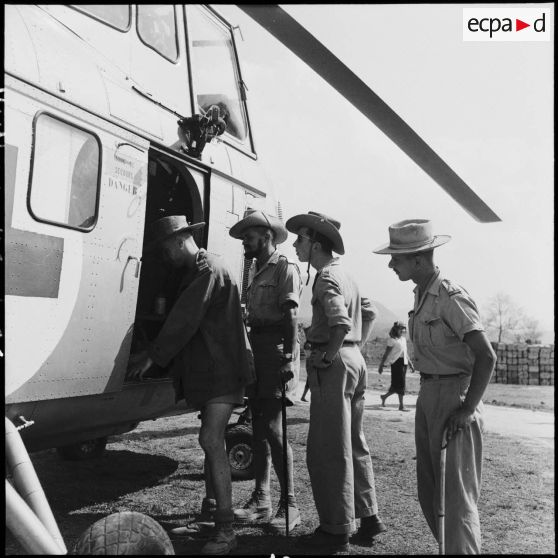 Des officiers autour d'un hélicoptère Sikorsky H-19 sur le camp de Muong Sai.