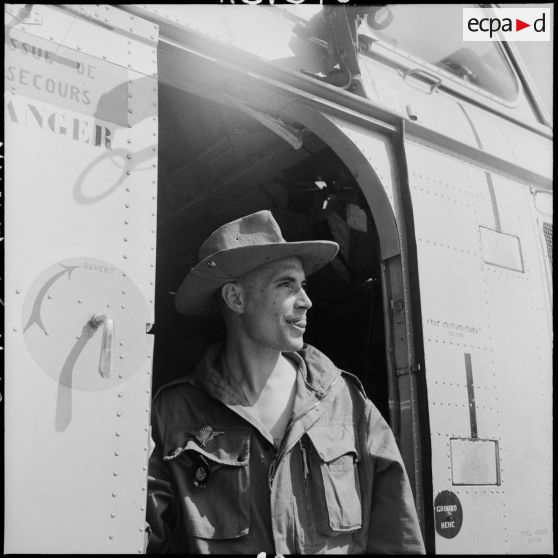 Un soldat breveté parachutiste devant un hélicoptère Sikorsky H-19 sur le camp de Muong Sai.