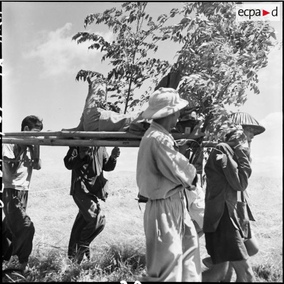 Transport d'un soldat de l'Union française sur un brancard par des Vietminh au cours d'un échange de prisonniers à Viet Tri.