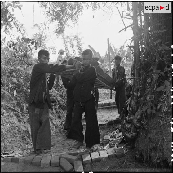 Transport de prisonniers de guerre des troupes de l'Union française sur des brancards au cours d'un échange de prisonniers avec le Vietminh à Viet Tri.