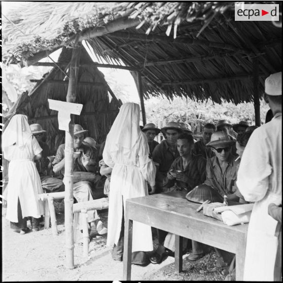 Dans la barque de transit des prisonniers, des infirmières de l'Armée populaire vietnamienne distribuent des tasses de thé aux futurs libérés.