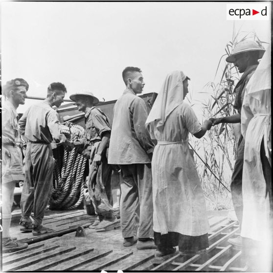 Des soldats de l'Union française donnent une dernière poignée de main aux infirmiers et infirmières de l'Armée populaire vietnamienne avant de monter sur le bateau lors de leur libération à Viet Tri.