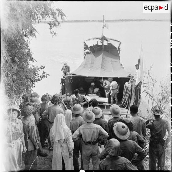 Départ d'un chaland de débarquement chargé de prisonniers de l'Union française libérés tandis que soldats et personnel médical de l'Armée populaire vietnamienne les saluent.