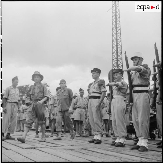 Sur les quais d'Haïphong, une section de la Légion étrangère présente les armes aux prisonniers de l'Union française libérés par le Vietminh à Sam Son.