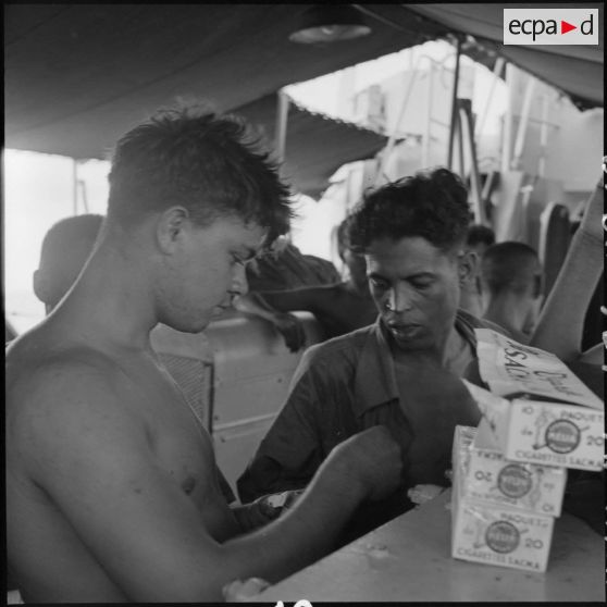 Des prisonniers libérés par le Vietminh perçoivent des paquets de cigarettes à bord d'un chaland de débarquement les rapatriant vers Haïphong.