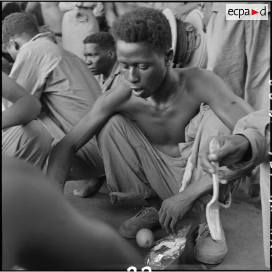 Des tirailleurs sénégalais libérés par le Vietminh reçoivent de la nourriture à bord d'un chaland de débarquement les rapatriant vers Haïphong.