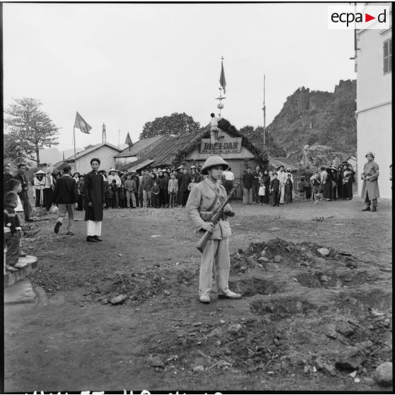 Les habitants de Campha attendent l'arrivée des troupes vietminh dans la ville, sous la garde d'éléments de la populaire vietminh et de la police militaire.