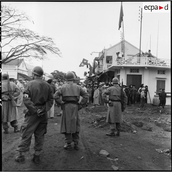 La police militaire et des journalistes sont postés au carrefour de Campha quelques instants avant l'arrivée des troupes vietminh dans la ville.