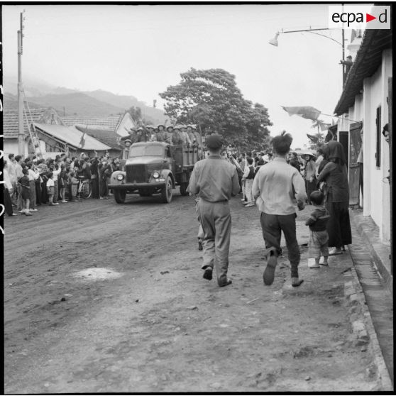 Montées sur camions Molotova, les troupes vietminh font leur entrée à Campha sous le regard de la population.