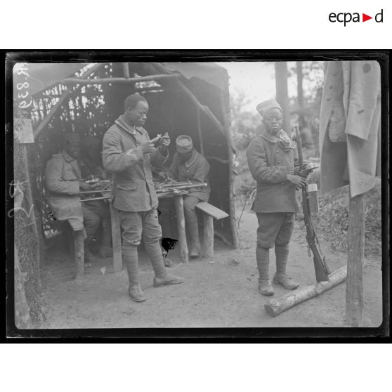 Bois d'Houssoy, près de Remaugis (Somme). Camp de tirailleurs sénégalais, 62e bataillon, Sénégalais nettoyant leurs fusils. [légende d'origine]