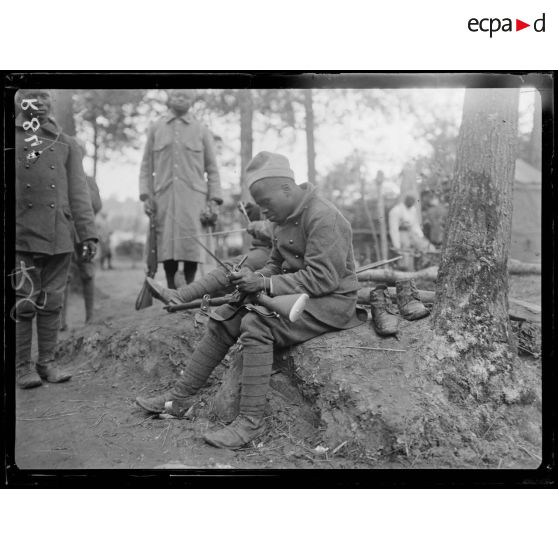 Bois d'Houssoy, près de Remaugis (Somme). Camp de tirailleurs sénégalais, 62e bataillon, Sénégalais nettoyant leurs fusils. [légende d'origine]