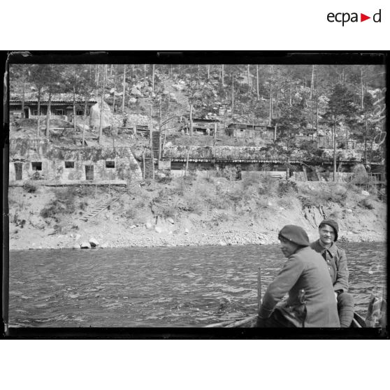 [Deux soldats à bord d'une embarcation face à un cantonnement.]