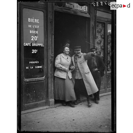 [Une autorité militaire indique une direction à une femme, à l'entrée d'un café.]