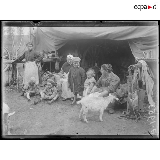 [Photographie d'une famille de réfugiés devant leur campement, en pleine campagne.]